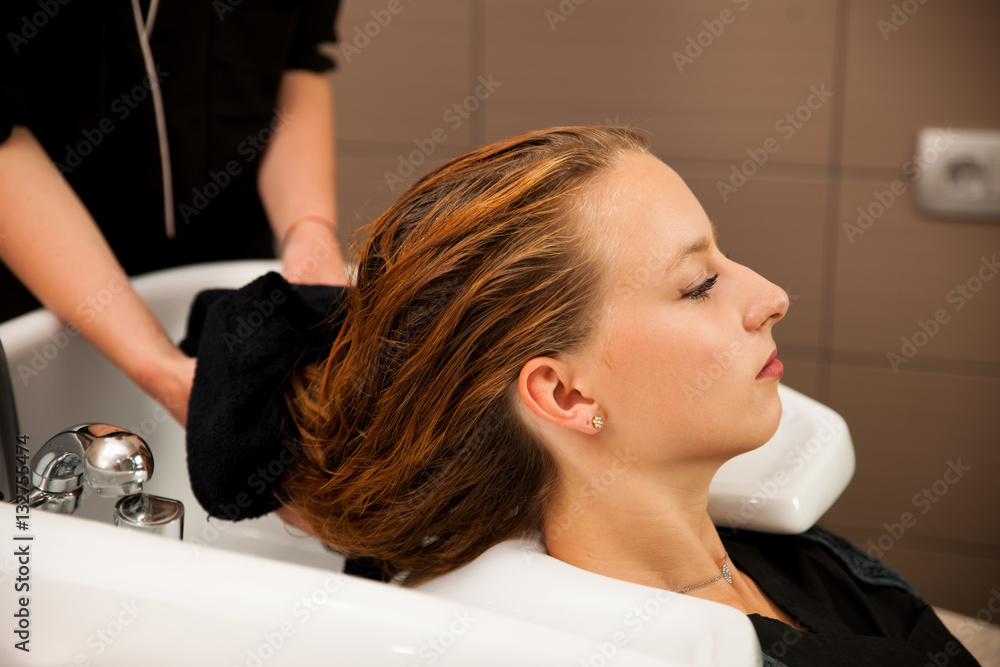Fototapeta premium Hair stylist at work - hairdresser washing hair to the customer