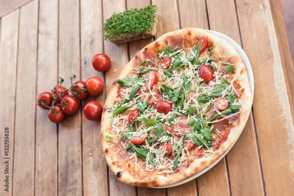 pizza on a wooden table with tomato and cheese