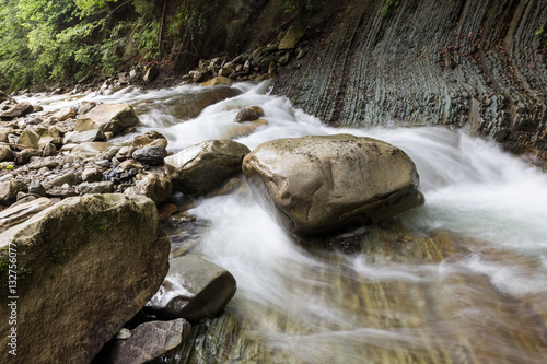 The huge stone lying in the river. Vibrant water.