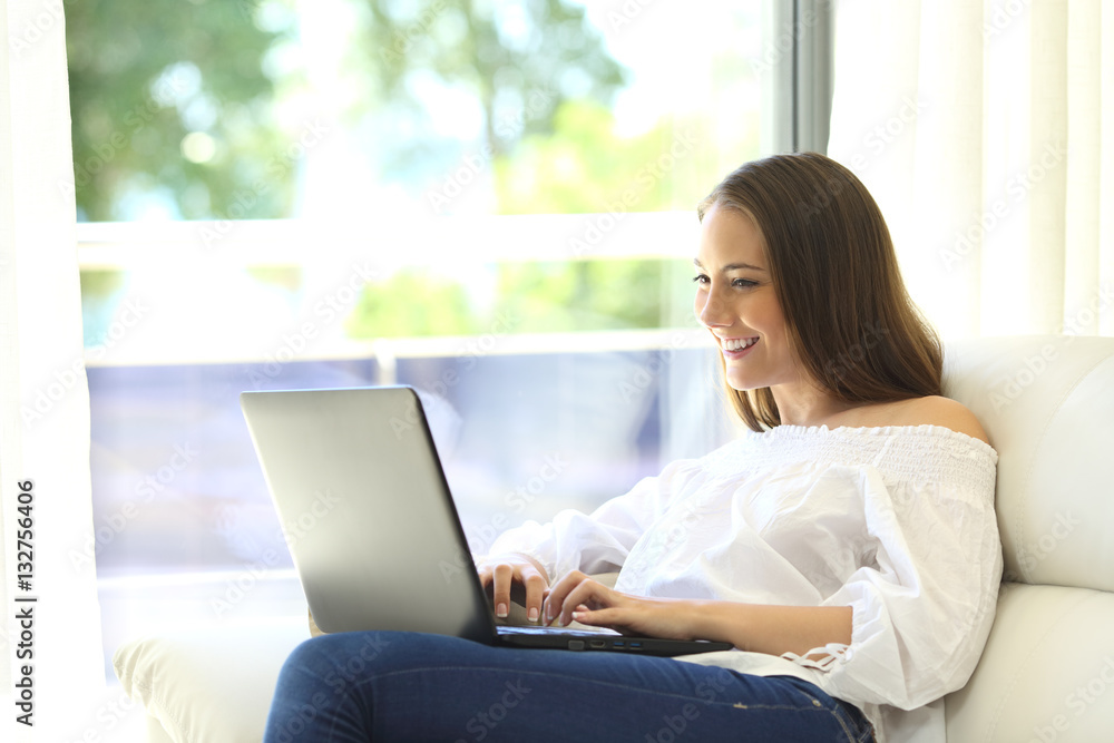 Housewife using a laptop sitting on couch Housewife using a laptop sitting on couch