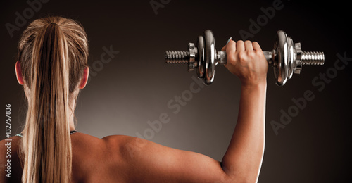 Fototapeta Naklejka Na Ścianę i Meble -  fit woman workout with dumbbells in gym studio photography of a