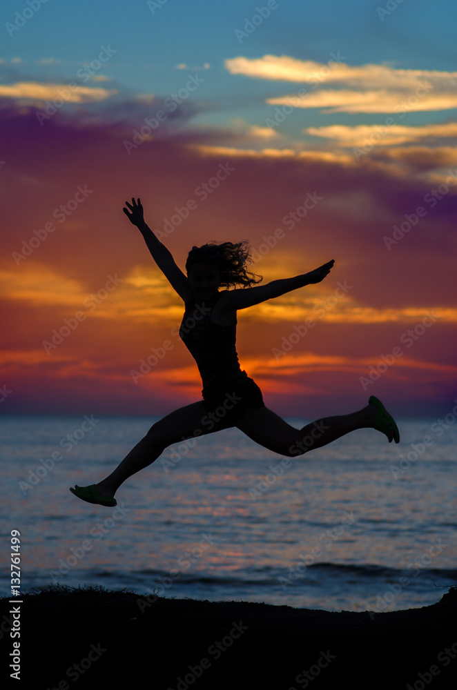 silhouette of jumping girl on a background of sea sunset silhouette of jumping girl on a background of sea sunset