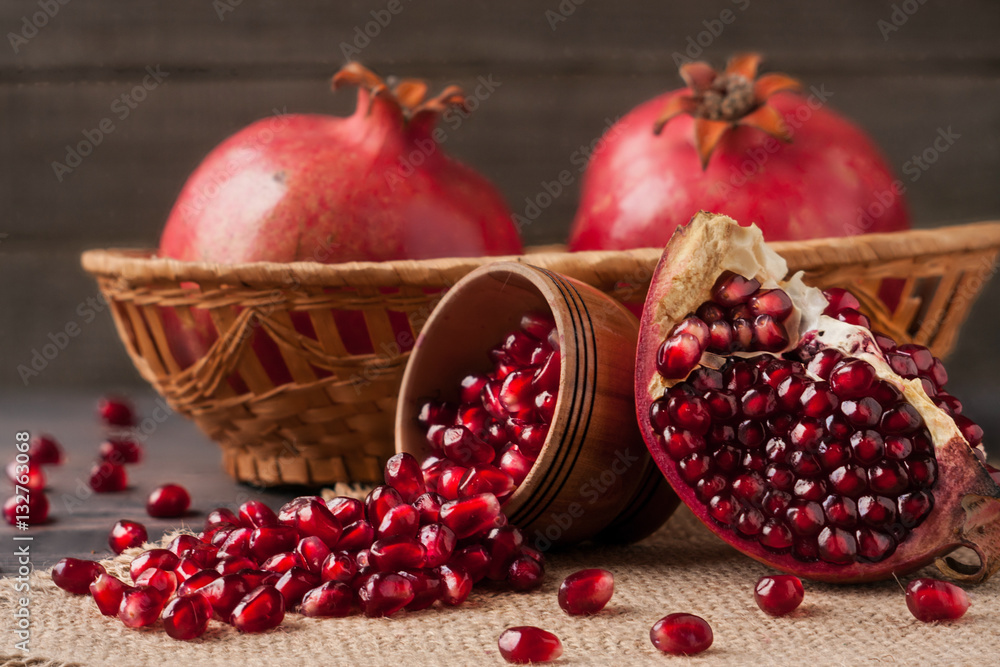 two pomegranate in a wicker basket and grains in the bowl on the old wooden board with sackcloth two pomegranate in a wicker basket and grains in the bowl on the old wooden board with sackcloth