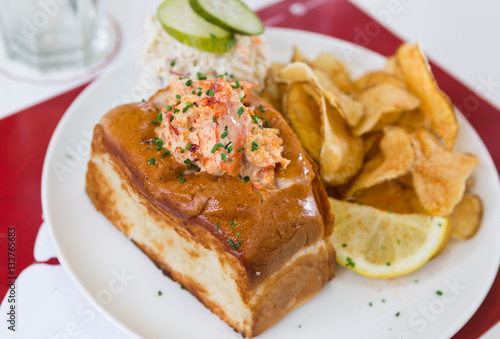 A cheese, prawn, seafood and tomato brioche sandwich, served with crisps and a wedge of lemon.