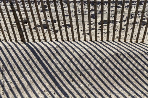 fence at the beach gives a harmonic shadow