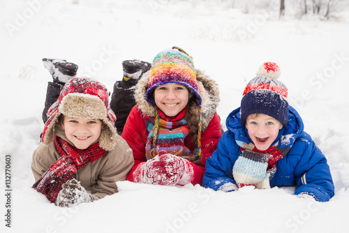 Three kids lying down together on winter snow