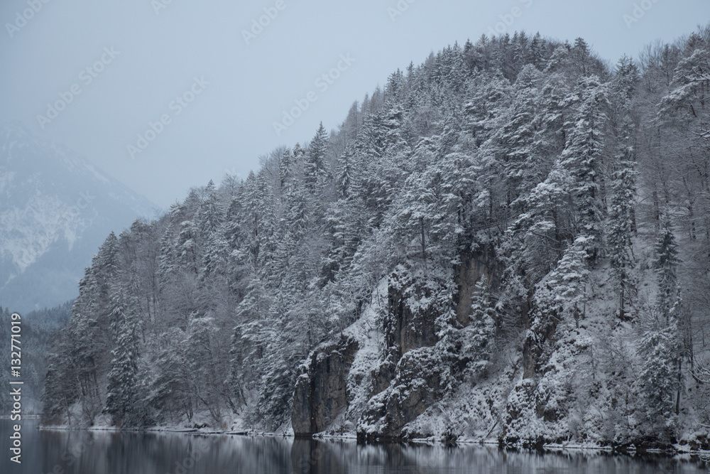 Fototapeta premium White snowy mountain at Alpsee lake in winter time. Germany.