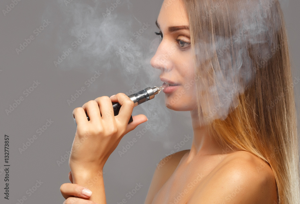 Fototapeta premium Young beautiful woman smoking ( vaping ) e-cigarette
