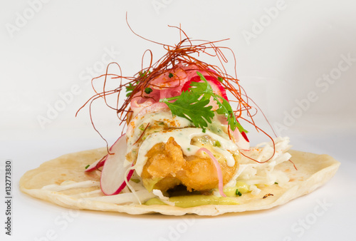 Photography Golden fried cod fish taco isolated on a white background, served with parsley, red onion hollandaise sauce, radish,  and a fresh wedge of lime