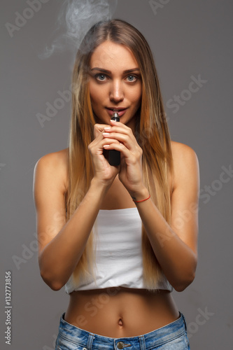 Young beautiful woman smoking ( vaping ) e-cigarette