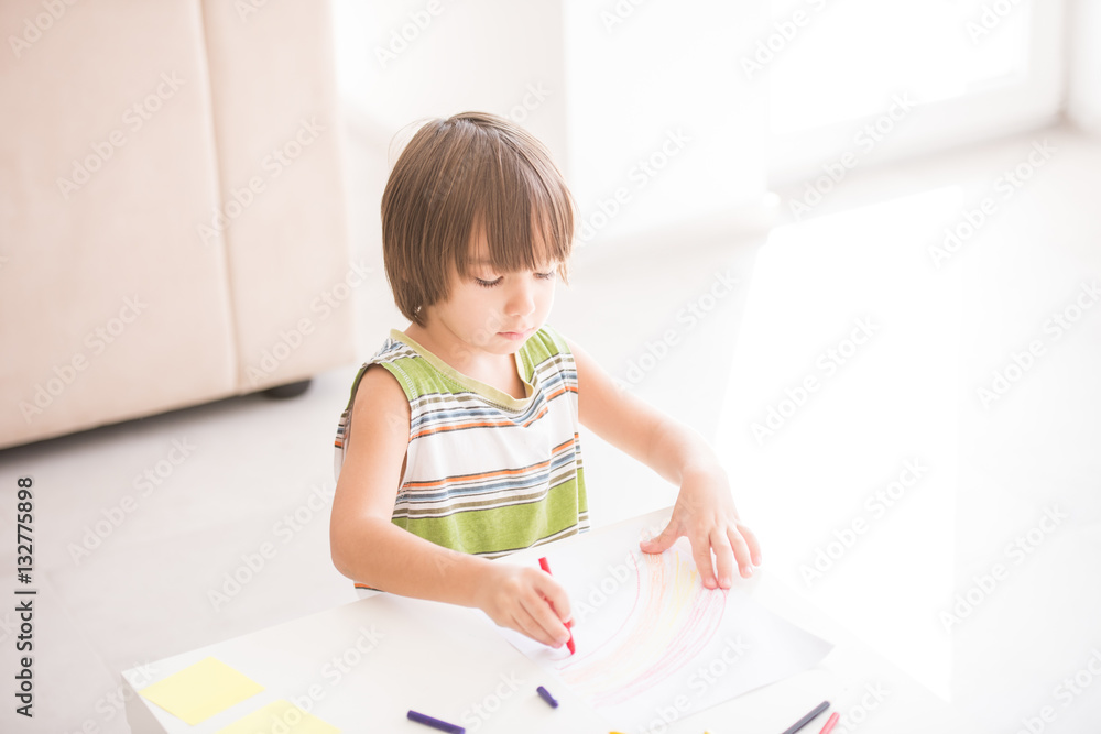 Cute boy drawing at home