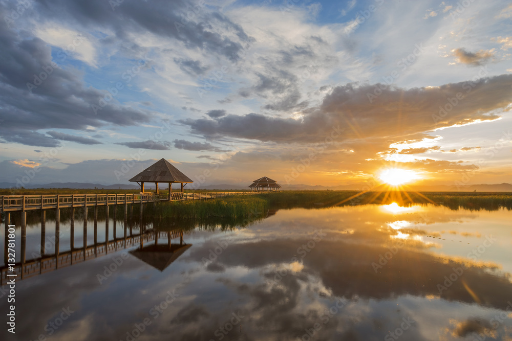 Fototapeta premium Wooden bridge laying on lake at sunset scenery