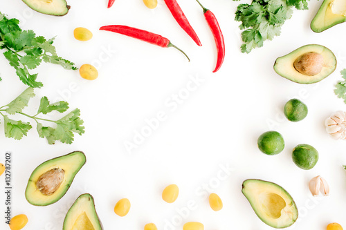 Frame made of raw food ingredients of guacamole: avocado, chili pepper, coriander, cherry tomato, lime, garlic. Flat lay, top view. Food concept.