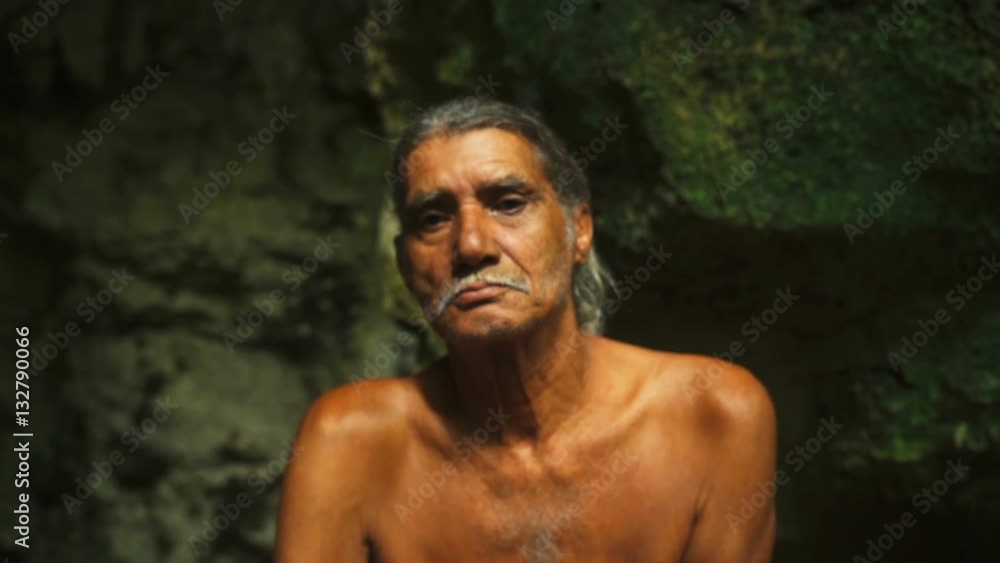Adult male in shorts sitting on a large rock in a deep cave