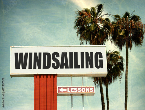 aged and worn vintage photo of windsailing lessons sign with palm trees