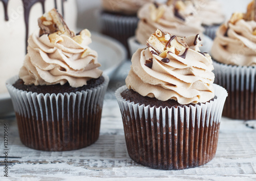 Chocolate cupcake with mousse cream icing on grunge white wooden background copy space