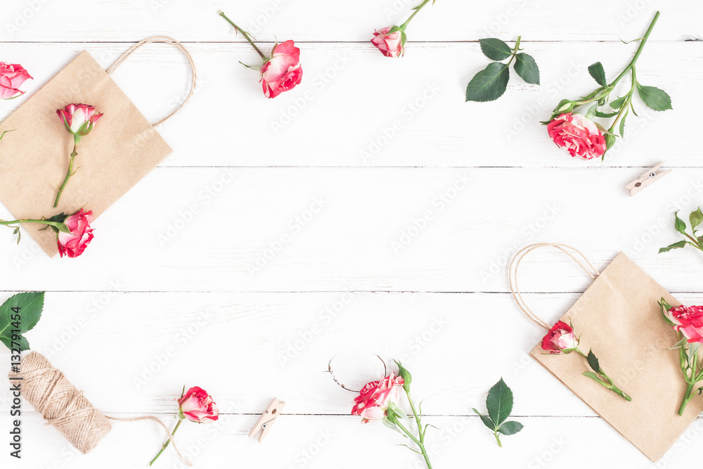 Flowers composition. Gift and rose flowers on wooden white background. Flat lay, top view