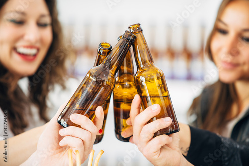 Four people cheering with bottled beer