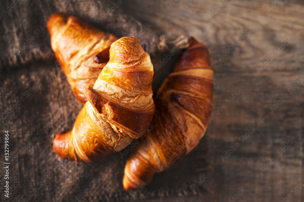 Golden fresh croissants  on old wooden background close up with