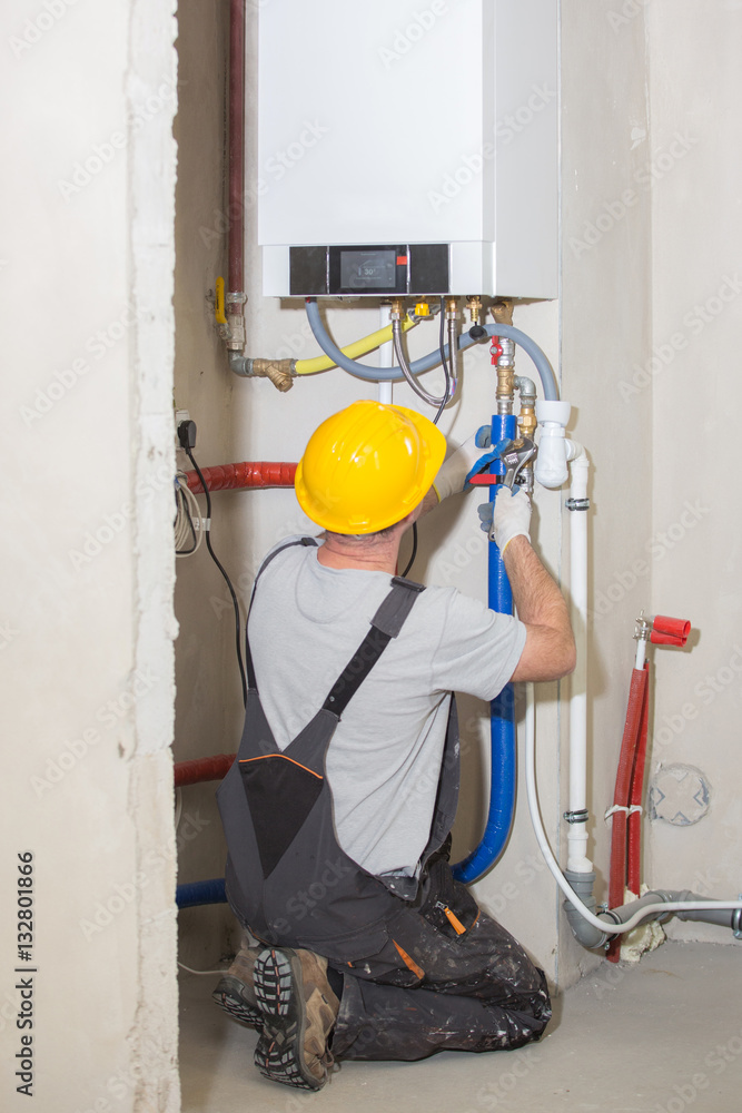Technician servicing heating boile, plumber
