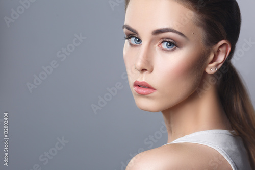 Beauty portrait of a pretty girl with natural makeup isolated on gray background.