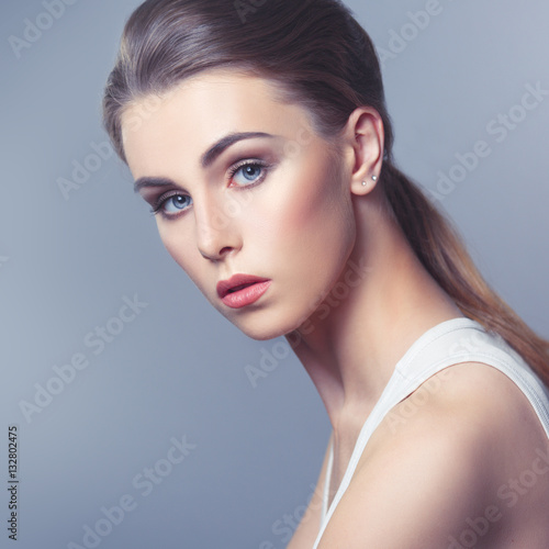 Beauty portrait of a pretty girl with natural makeup isolated on gray background.