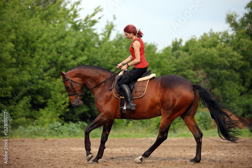 Equestrian girl horseback riding along forest trail