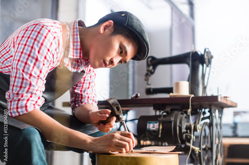 Asian shoe or belt maker in his leather workshop