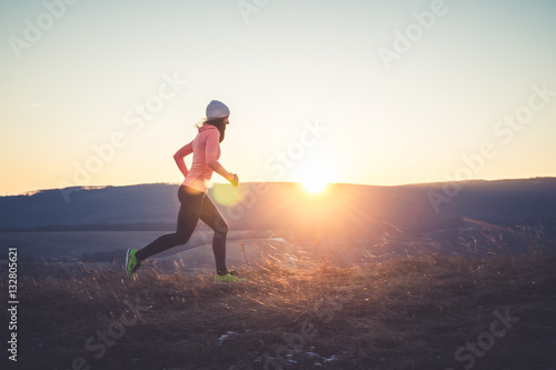 Fototapeta Naklejka Na Ścianę i Meble -  Runner girl on top of the hill in sunset