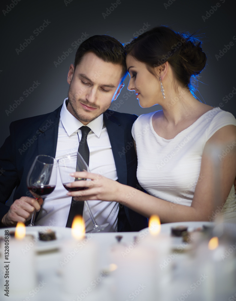 Couple clinking red wine glasses at table