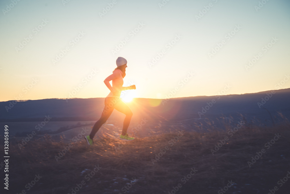 Runner girl on top of the hill in sunset