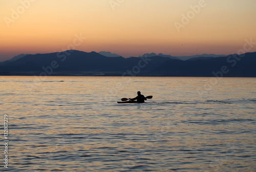 Lonely paddler on the lake during the sunset