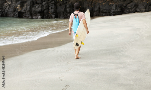 Disappointed surfer with backpack leaving beach, having no chanc photo