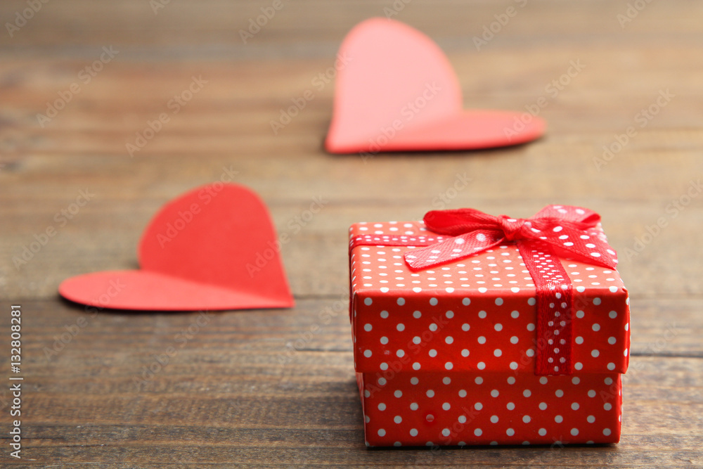 Red gift box with decorative hearts on a wooden background. Red gift box with decorative hearts on a wooden background.