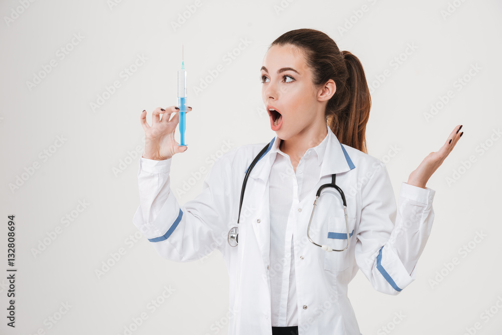 Portrait of amazed pretty young woman standing and holding syringe Portrait of amazed pretty young woman standing and holding syringe