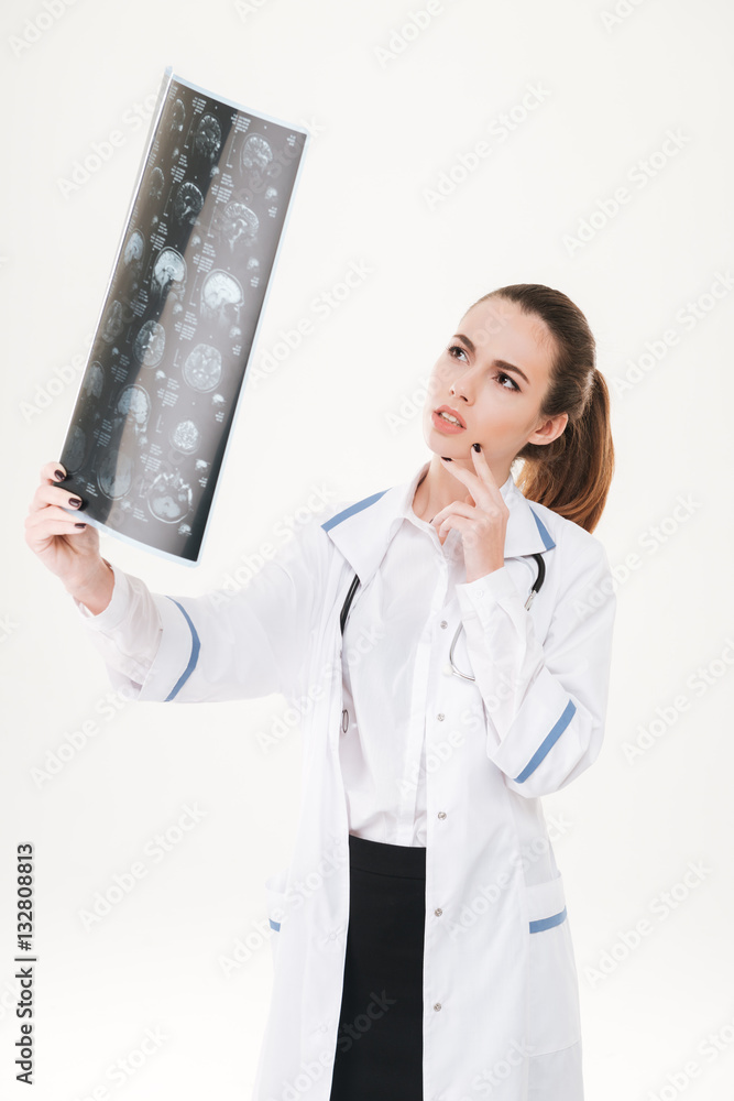 Thoughtful young woman doctor holding and looking at radiography Thoughtful young woman doctor holding and looking at radiography