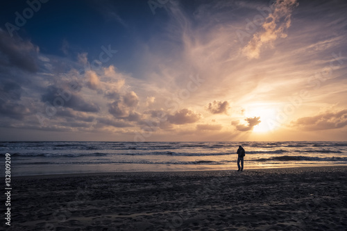 man walking on the sea shore at sunset