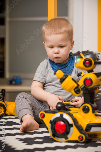 Little toddler boy playing with funny robot toy at home, indoors. Innovation technology concept. Children and technology.