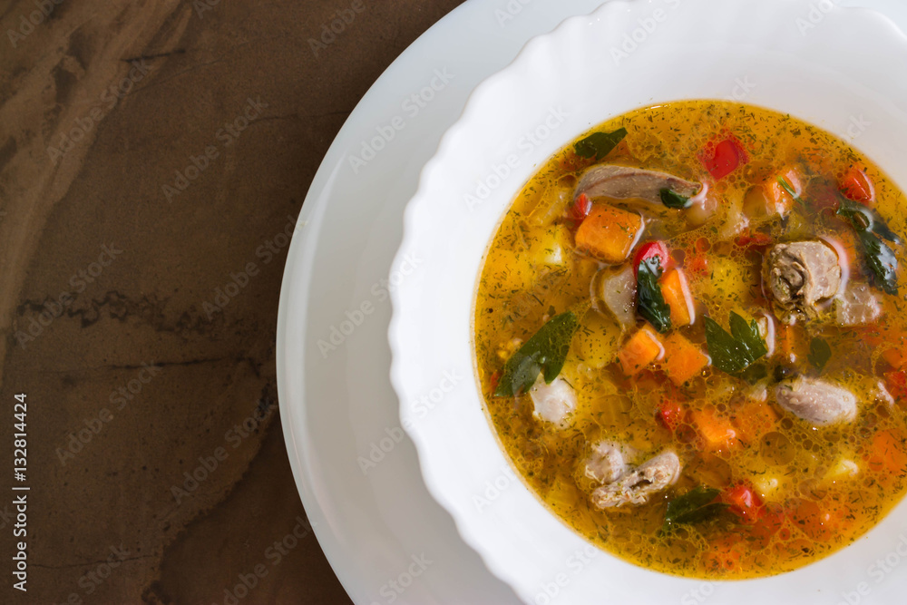 Vegetable soup with chicken giblets in a white bowl on a marble table Vegetable soup with chicken giblets in a white bowl on a marble table
