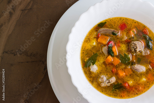 Konstfotografi Vegetable soup with chicken giblets in a white bowl on a marble table