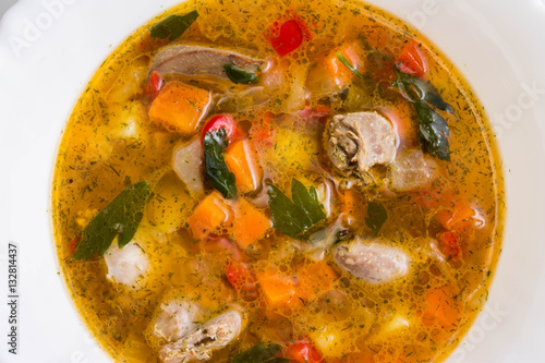 Fotografie Vegetable soup with chicken giblets in a white bowl on a marble table