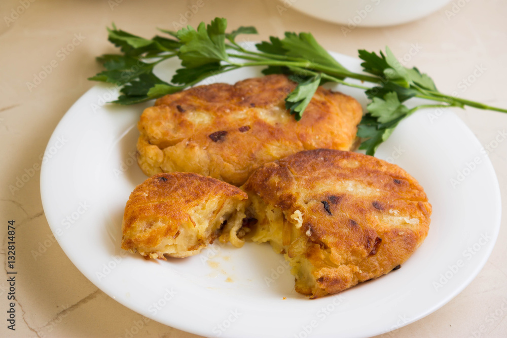 Potato patties with fried onions on a white plate Potato patties with fried onions on a white plate