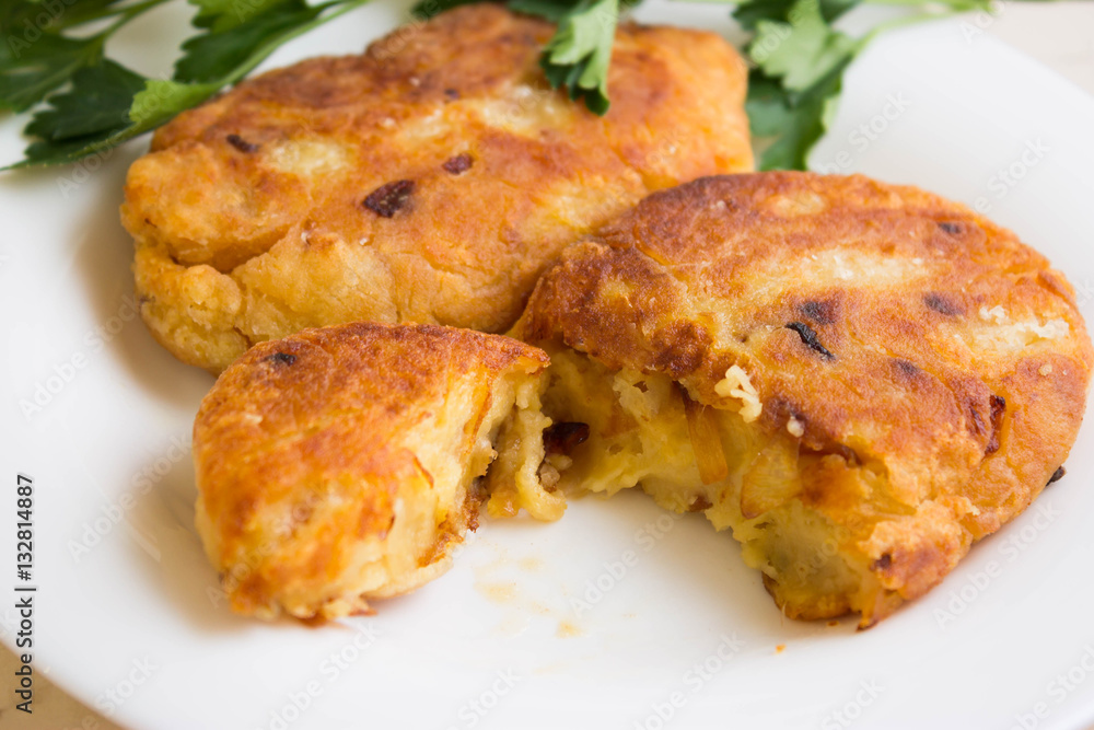 Potato patties with fried onions on a white plate Potato patties with fried onions on a white plate