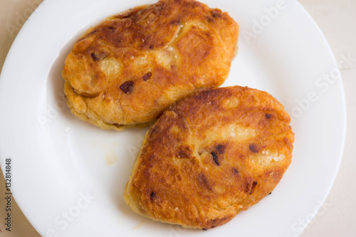 Potato patties with fried onions on a white plate