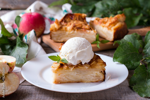 Closeup of a slice of apple pie with a scoop of ice cream on a plate