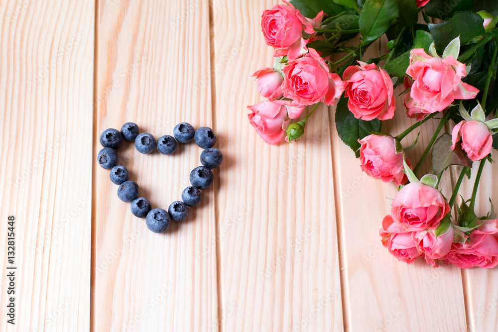 Beautiful roses and heart on a wooden background