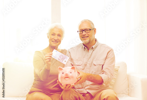 senior couple with money and piggy bank at home