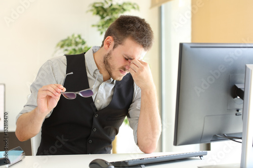 Businessman suffering eyestrain at office photo