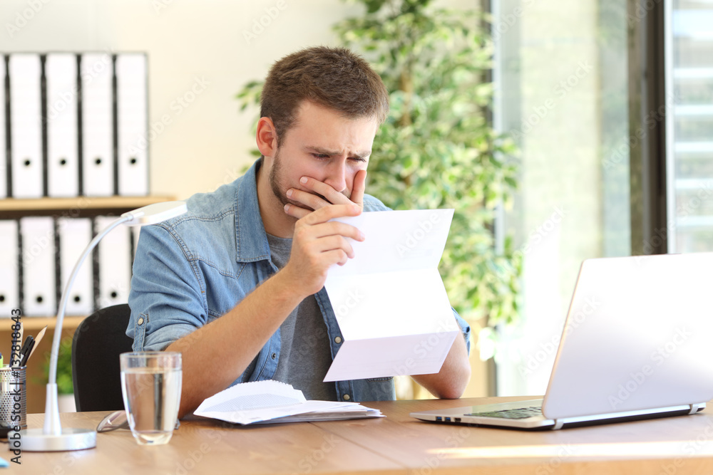 Worried entrepreneur reading a letter Worried entrepreneur reading a letter