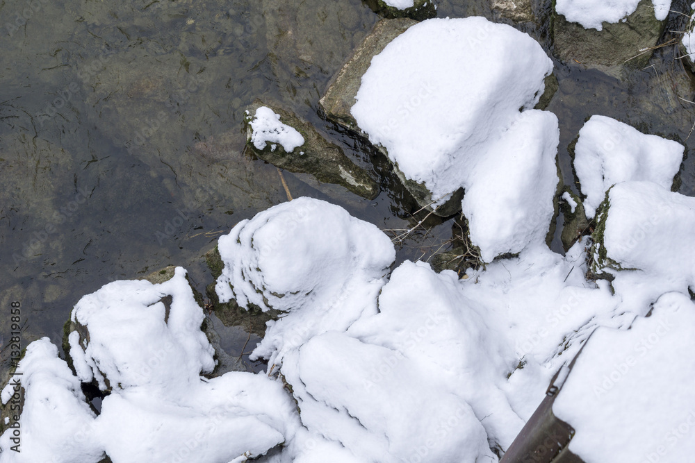 Schnee auf Steinen im Fluss 
